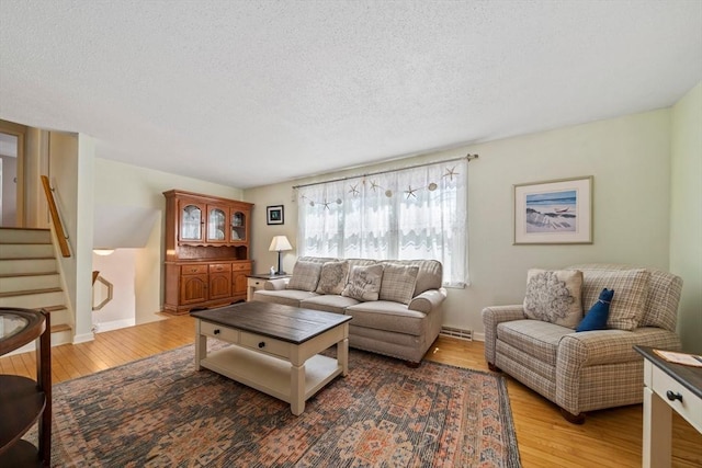 living room with stairway, wood-type flooring, a textured ceiling, and visible vents