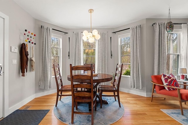 dining area with an inviting chandelier, light wood-style flooring, baseboards, and visible vents
