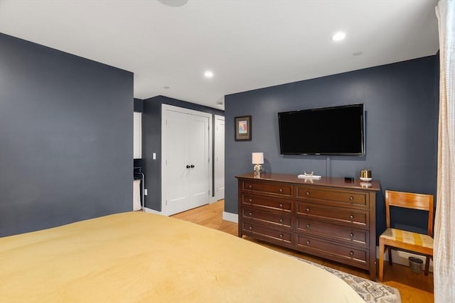 bedroom with a closet, light wood-type flooring, baseboards, and recessed lighting