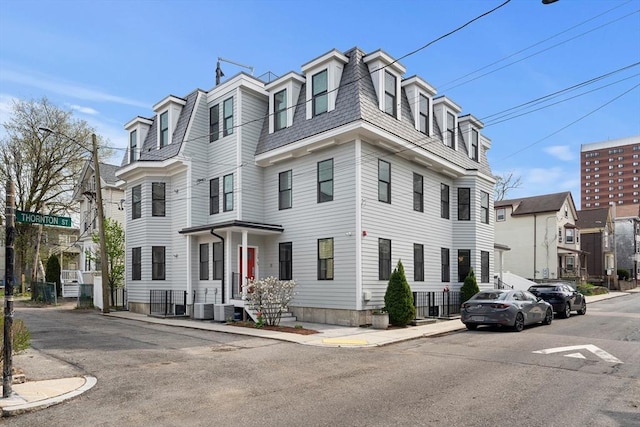 victorian home featuring mansard roof and central AC