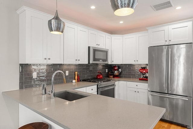 kitchen with a peninsula, light countertops, appliances with stainless steel finishes, and a sink