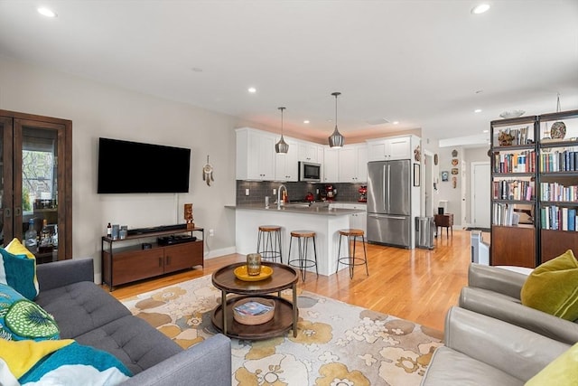 living area with light wood-style flooring and recessed lighting