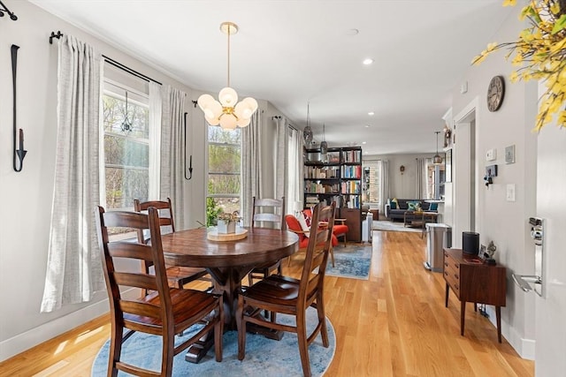 dining space with light wood finished floors, baseboards, a notable chandelier, and recessed lighting