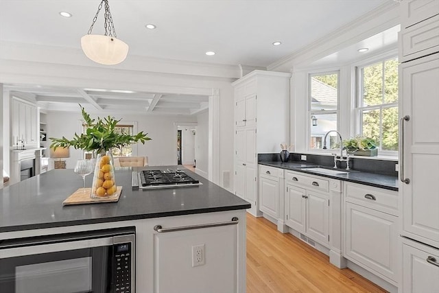 kitchen with stainless steel appliances, a sink, dark countertops, white cabinetry, and recessed lighting