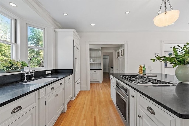 kitchen featuring oven, a sink, dark countertops, ornamental molding, and white cabinets