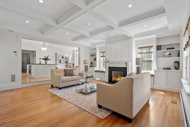 living area with light wood finished floors, a glass covered fireplace, coffered ceiling, beamed ceiling, and built in shelves