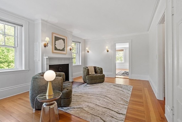 sitting room featuring healthy amount of natural light, light wood finished floors, ornamental molding, and a fireplace
