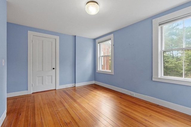 spare room featuring baseboards and light wood-style floors
