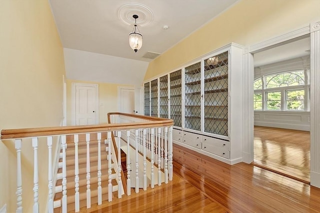 hall with wood-type flooring and an upstairs landing