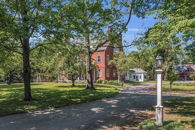 view of property's community featuring a yard and asphalt driveway