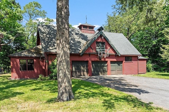 rustic home featuring roof with shingles, a front lawn, driveway, and a garage