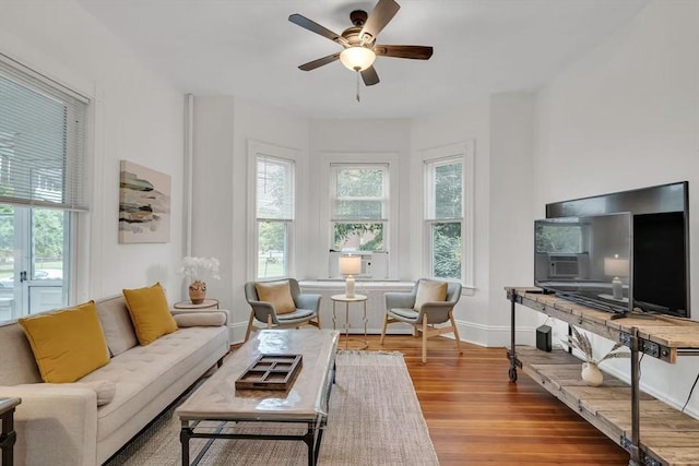 living room featuring ceiling fan, baseboards, a wealth of natural light, and wood finished floors