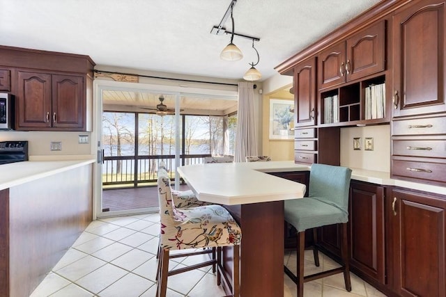 kitchen featuring light tile patterned floors, light countertops, a peninsula, a breakfast bar, and black range with electric cooktop
