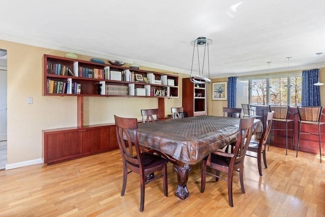 dining room featuring light wood-style floors, baseboards, and ornamental molding