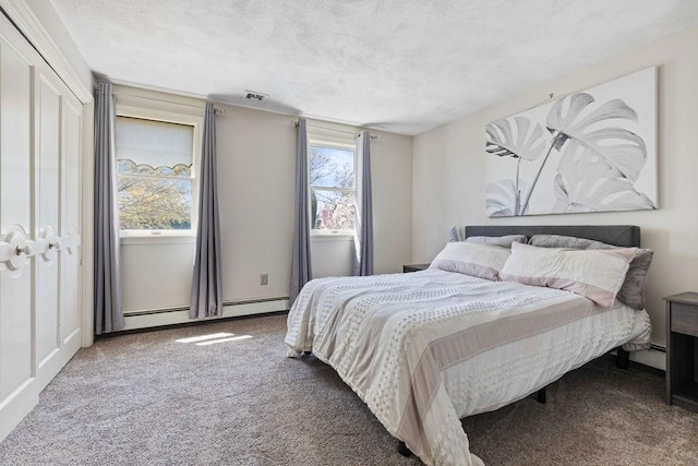 bedroom with carpet floors, baseboard heating, a textured ceiling, and visible vents