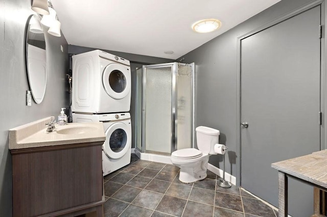 full bathroom featuring tile patterned flooring, a shower stall, vanity, toilet, and stacked washer and clothes dryer