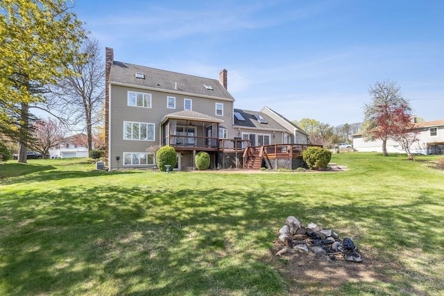 rear view of house featuring a lawn, a deck, and a chimney