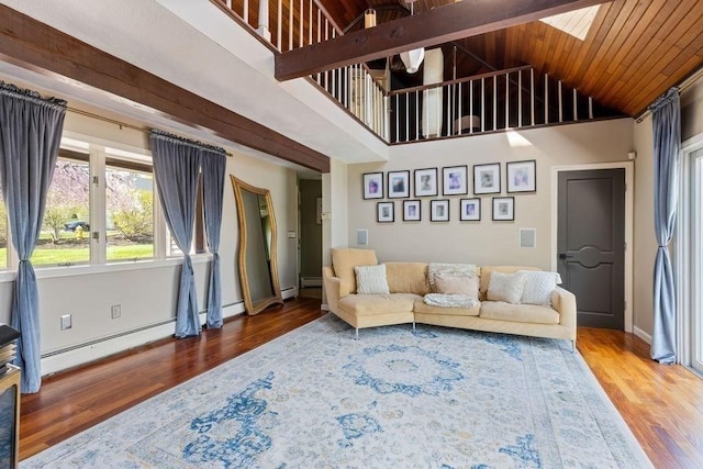 living area featuring baseboard heating, a skylight, wood finished floors, and high vaulted ceiling