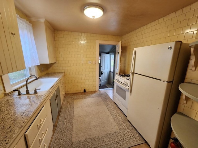 kitchen featuring white appliances, white cabinets, sink, tile walls, and light stone counters