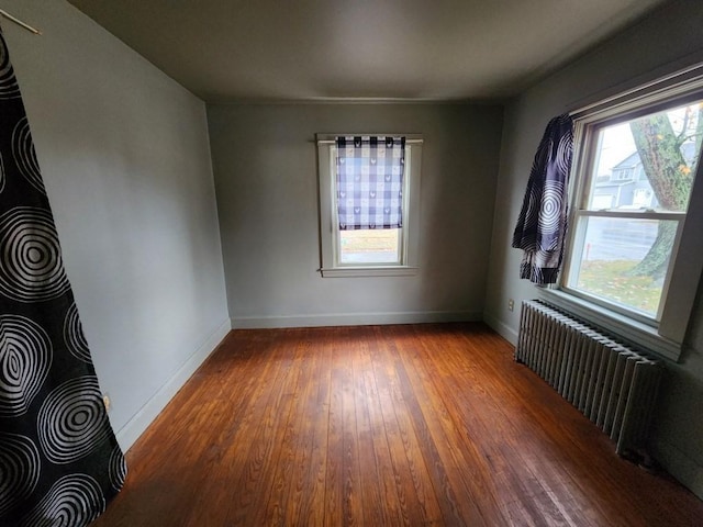 spare room with dark hardwood / wood-style flooring and radiator