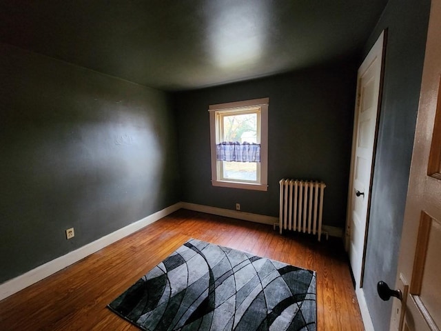 bedroom featuring radiator heating unit and wood-type flooring