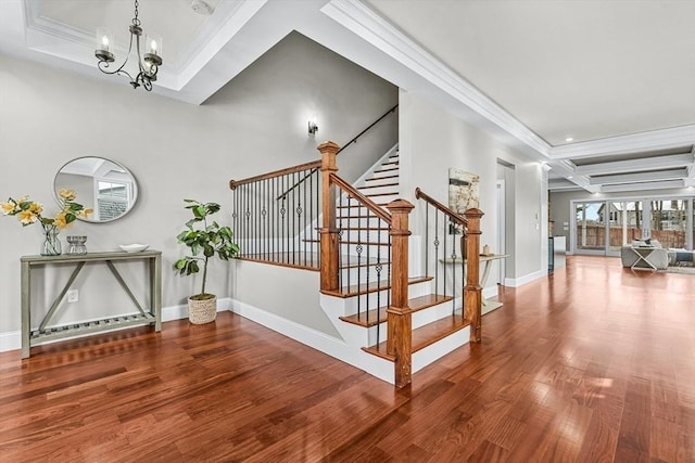 staircase with ornamental molding, wood-type flooring, coffered ceiling, and a chandelier