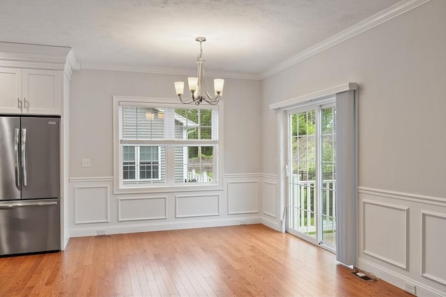 295 Sewall St Unit 295, Boylston, MA 01505 - unfurnished dining area featuring a chandelier, light wood-type flooring, a wainscoted wall, a decorative wall, and crown molding