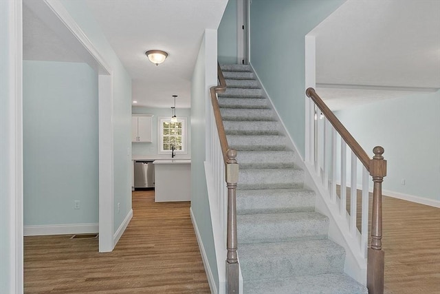 staircase with hardwood / wood-style flooring and sink