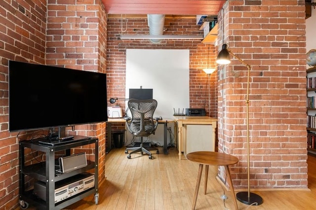 office area featuring wood-type flooring and brick wall