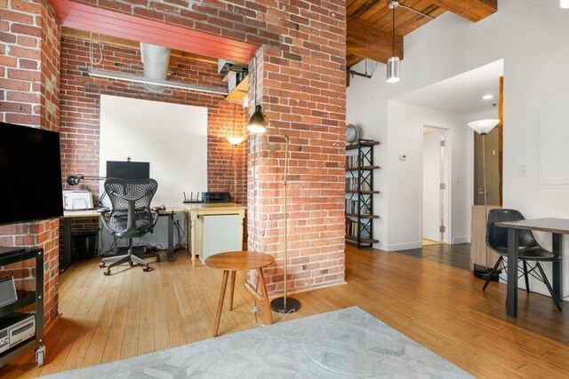 office featuring wood finished floors, brick wall, beamed ceiling, and baseboards