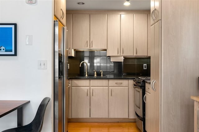 kitchen with electric stove, light brown cabinets, tasteful backsplash, and a sink