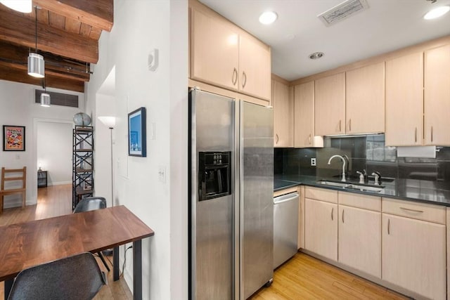 kitchen with appliances with stainless steel finishes, a sink, dark countertops, light wood-style flooring, and recessed lighting
