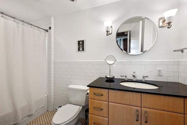 full bathroom featuring tile walls, toilet, vanity, a wainscoted wall, and shower / tub combo with curtain