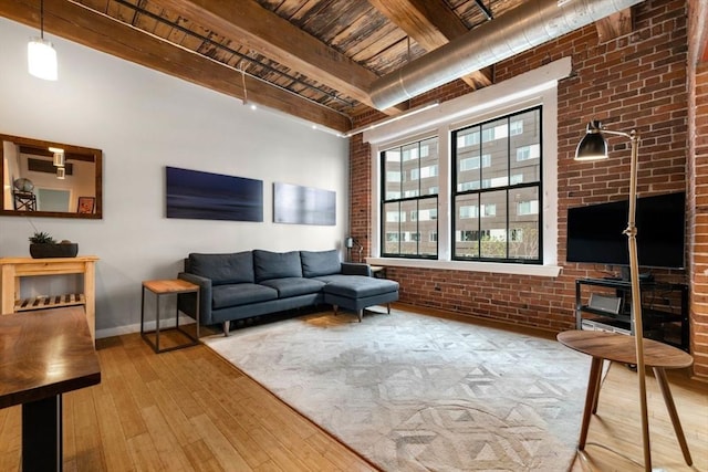 living area with brick wall, hardwood / wood-style flooring, wood ceiling, beam ceiling, and baseboards
