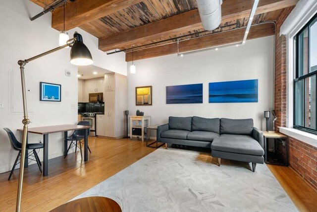 living area with light wood finished floors, beam ceiling, brick wall, and wood ceiling
