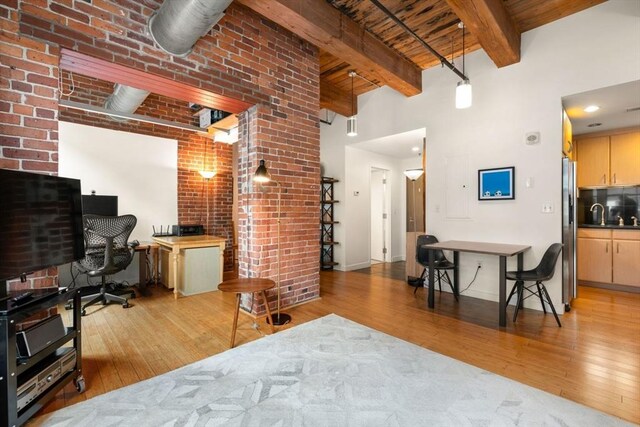 living room with wood finished floors, brick wall, a towering ceiling, wood ceiling, and beam ceiling