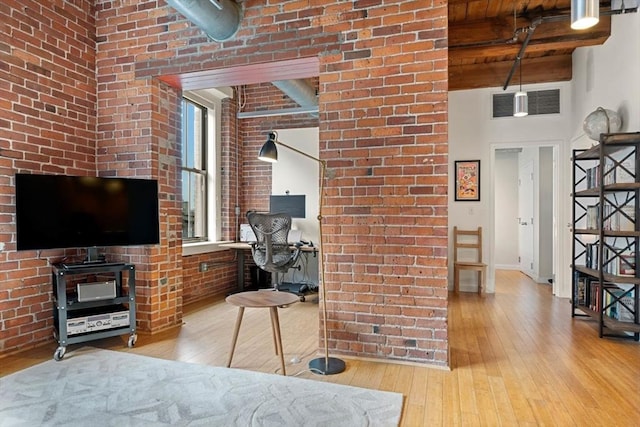 bedroom featuring hardwood / wood-style floors, wooden ceiling, beamed ceiling, brick wall, and baseboards