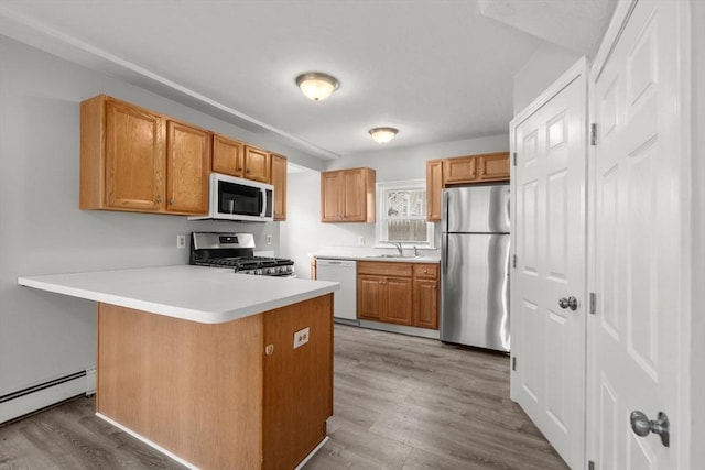 78-82 3rd St, Lowell, MA 01850 - kitchen with stainless steel appliances, a baseboard radiator, a peninsula, wood finished floors, and light countertops