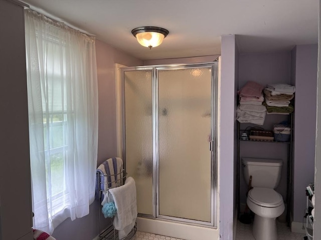 bathroom with a shower with shower door and toilet