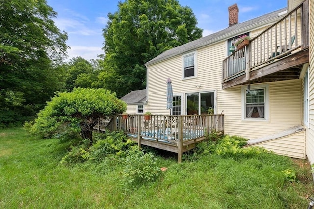 back of property featuring a wooden deck and a lawn