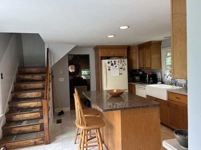 kitchen with a kitchen breakfast bar, a center island, sink, and white appliances