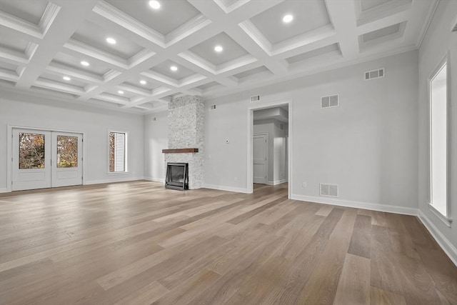 unfurnished living room featuring beamed ceiling, light hardwood / wood-style floors, a fireplace, and coffered ceiling