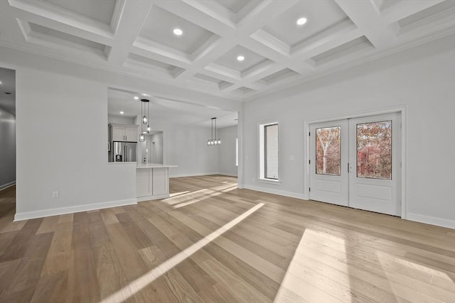 unfurnished living room with light hardwood / wood-style floors, french doors, beam ceiling, and coffered ceiling