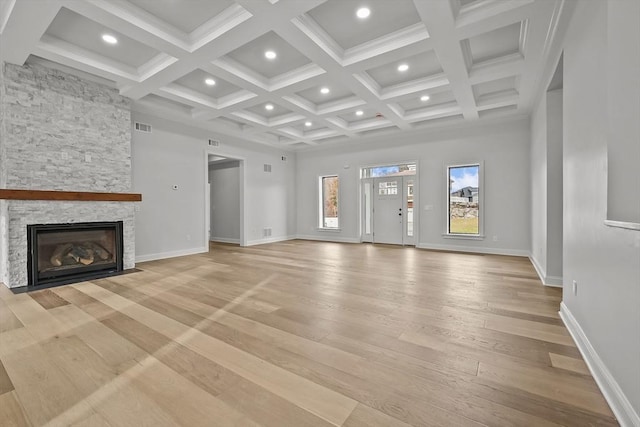 unfurnished living room featuring coffered ceiling, light hardwood / wood-style flooring, beamed ceiling, a fireplace, and a high ceiling