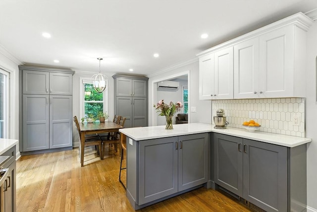 6 Flagg Dr, Framingham, MA 01702 - kitchen featuring gray cabinetry, a wall mounted AC, light countertops, crown molding, and a peninsula