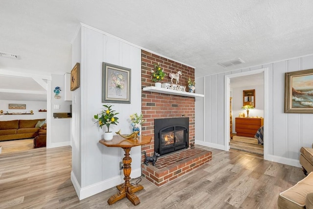 living room featuring a fireplace, light hardwood / wood-style flooring, and a textured ceiling