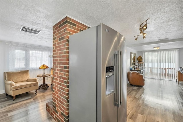 kitchen with plenty of natural light, wood-type flooring, stainless steel fridge with ice dispenser, and a textured ceiling