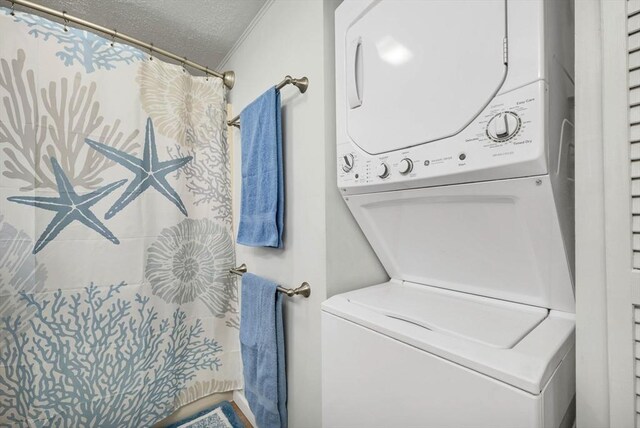 clothes washing area featuring a textured ceiling and stacked washer / drying machine