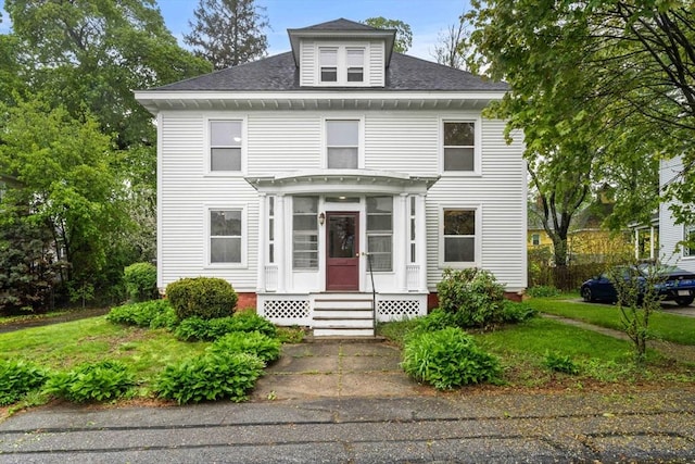 traditional style home with a shingled roof and a front lawn