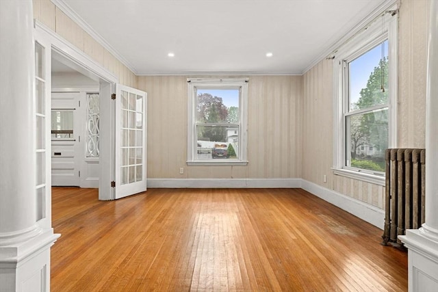 unfurnished room featuring radiator heating unit, light wood finished floors, healthy amount of natural light, and ornamental molding